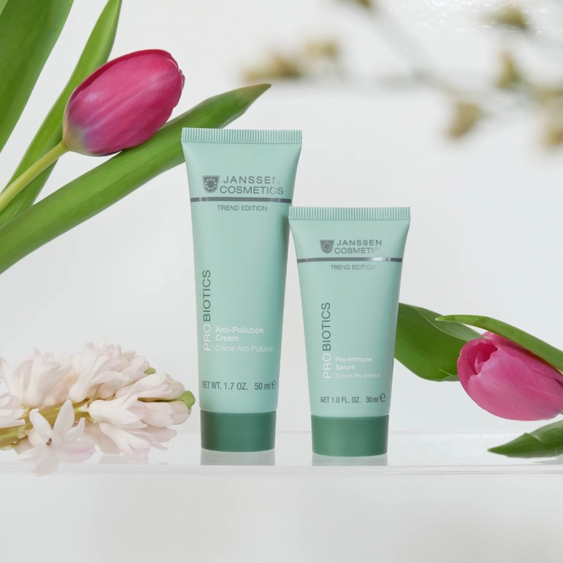 Deux produits Probiotics de Janssen Cosmetics, entourés de tulipes roses, présentés sur un fond clair.